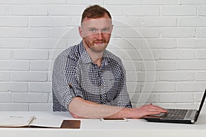 Businessman sitting at the table and working on the computer. It solves important business tasks. He is successful and well-traine