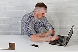 Businessman sitting at the table and working on the computer. It solves important business tasks. He is successful and well-traine