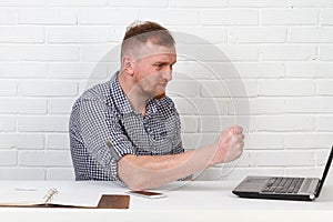 Businessman sitting at the table and working on the computer. It solves important business tasks. He is successful and well-traine
