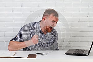 Businessman sitting at the table and working on the computer. It solves important business tasks. He is successful and well-traine