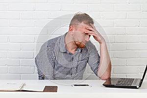 Businessman sitting at the table and working on the computer. It solves important business tasks. He is successful and well-traine