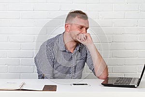 Businessman sitting at the table and working on the computer. It solves important business tasks. He is successful and well-traine