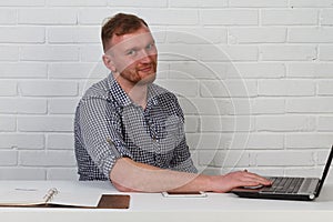 Businessman sitting at the table and working on the computer. It solves important business tasks. He is successful and well-traine