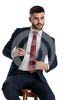 Businessman sitting and taking off glases with cool attitude