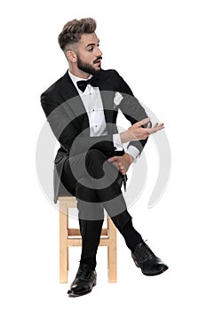 Businessman sitting and talking with someone aside intrigued