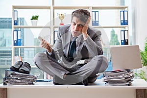 The businessman sitting on top of desk in office