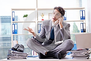 The businessman sitting on top of desk in office