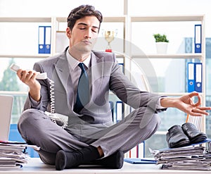 Businessman sitting on top of desk in office