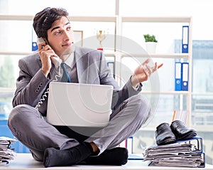 Businessman sitting on top of desk in office