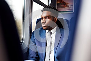 Businessman Sitting In Train Commuting To Work Looking Out Of Window