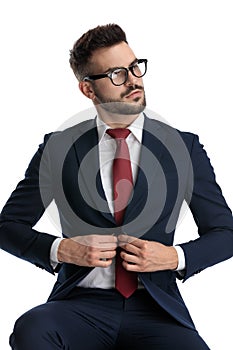 Businessman sitting and unbuttoning his jacket with tough attitude
