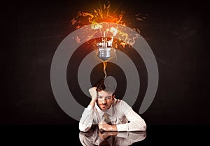 Businessman sitting under a blowing idea bulb