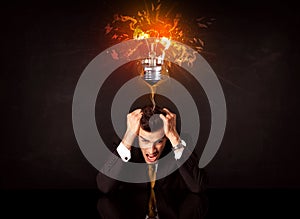 Businessman sitting under a blowing idea bulb