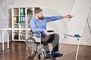 Businessman sitting in a wheelchair and drawing a chart on a board