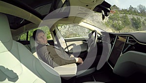 Deeply asleep businessman behind the steering wheel in self-driving electric car