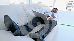 Businessman sleeping on couch with his laptop