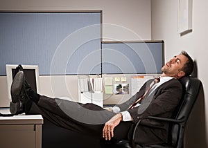 Businessman sleeping at desk with feet up