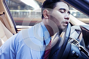 Businessman sleeping on the steering wheel