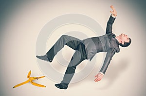 Businessman slipping and falling from a banana peel