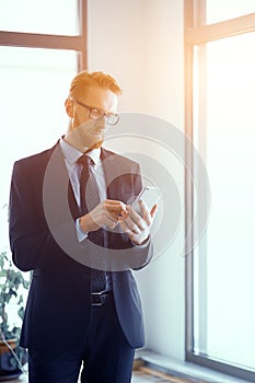 Businessman with smartphone in bright sunny office