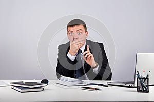 Businessman with smartphone holding his finger in front of his mouth and making silence gesture shh