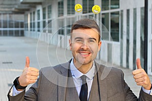 Businessman with smiley faces antennas giving a thumbs up