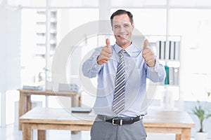 Businessman smiling at camera with thumbs up