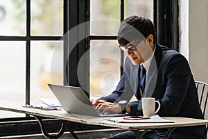 Businessman with smiling face working with laptop computer in office