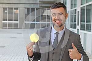 Businessman smiling while holding a big coin