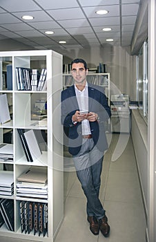Businessman smiling and holding smartphone in office
