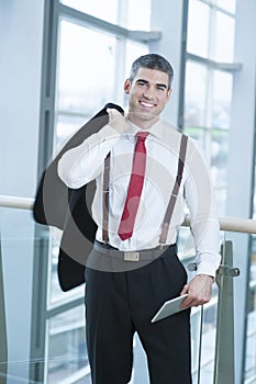 Businessman smiling and looking at camera with jacket over shoulder