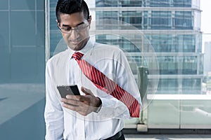 Businessman smiling while reading information on the mobile phone