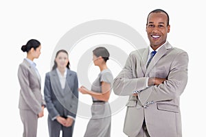 Businessman smiling with three co-workers talking in the background