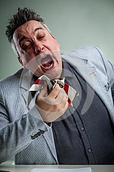 Businessman sneezing on his necktie