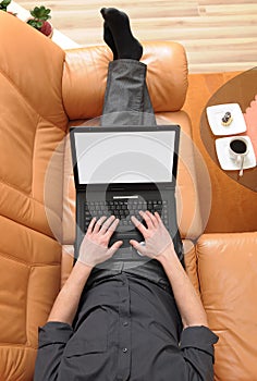 Businessman on the sofa with a laptop and coffee.