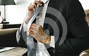 Businessman solo putting on neck tie