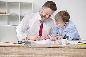 Businessman with son drawing at table