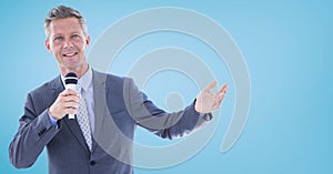 Businessman speaking with microphone against blue background
