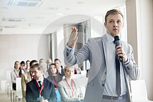 Businessman speaking through microphone during seminar in convention center