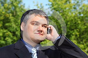 Businessman speaking by phone outdoor in summer photo