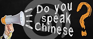 A businessman speaks into a loudspeaker, next to the text -Do you speak chinese. No face visible