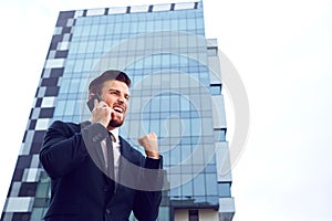 Businessman speaks on the phone outdoors.