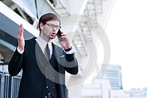 Businessman speaks by phone wave his hand in frustration.