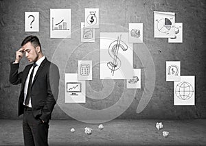 Businessman speculating with business posters on concrete wall and pieces of paper at the floor