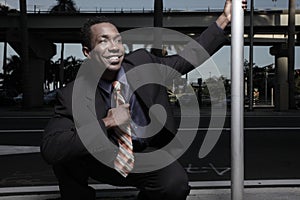 Businessman squatting and smiling on the street