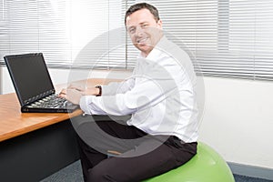 businessman on stability ball working laptop