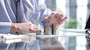 Businessman stacking coins on table, business growth concept. Hand puts coin to stack.