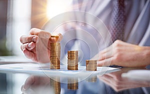 Businessman stacking coins on table, business growth concept. Hand puts coin to stack.