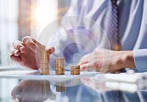 Businessman stacking coins on table, business growth concept. Hand puts coin to stack.