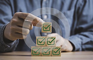 Businessman stacking green correct sign symbol which print screen on wooden block cube for document and project approve concept